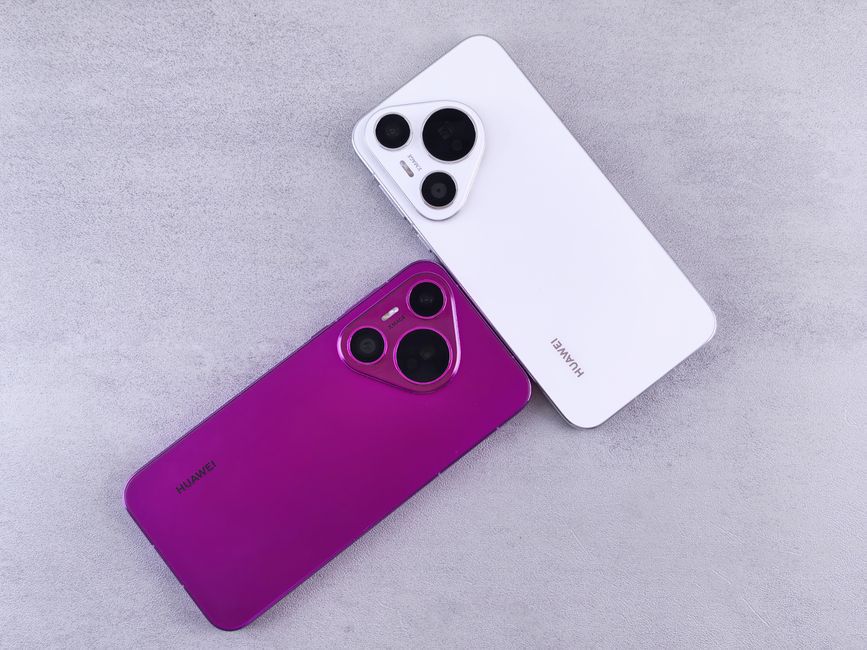 Two Huawei smartphones, one white and one purple, on a textured concrete surface.