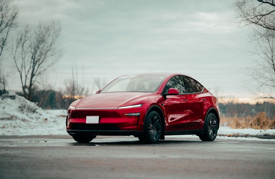 Red electric car parked outdoors, showcasing sleek design amidst winter scenery.