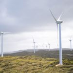 Majestic wind turbines harnessing energy in a vast green landscape under cloudy skies.