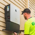 A skilled technician working on the installation of a solar inverter system outdoors. Energy efficiency solution.