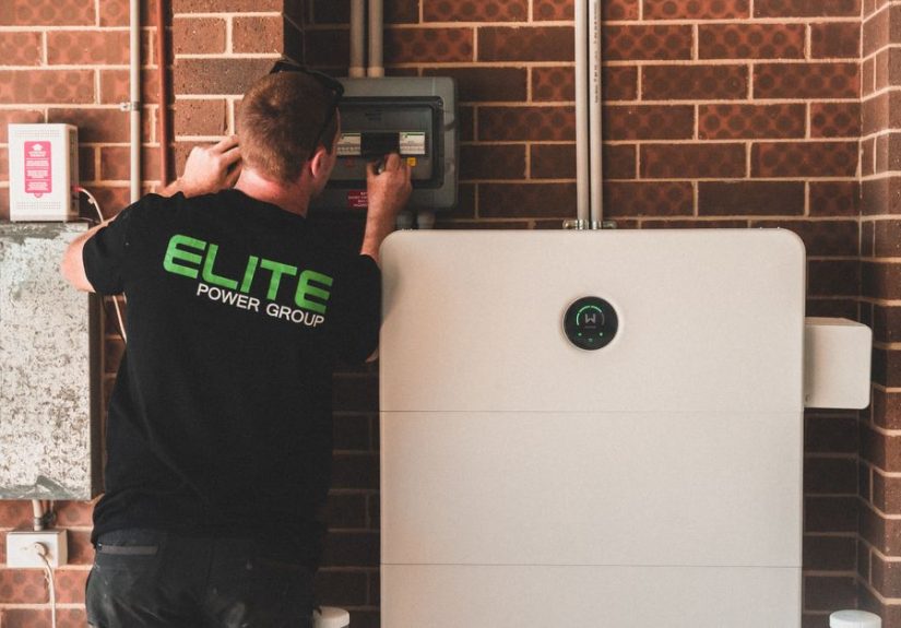 Electrician installing a home energy battery storage unit. Renewable and sustainable energy solution for residential use.