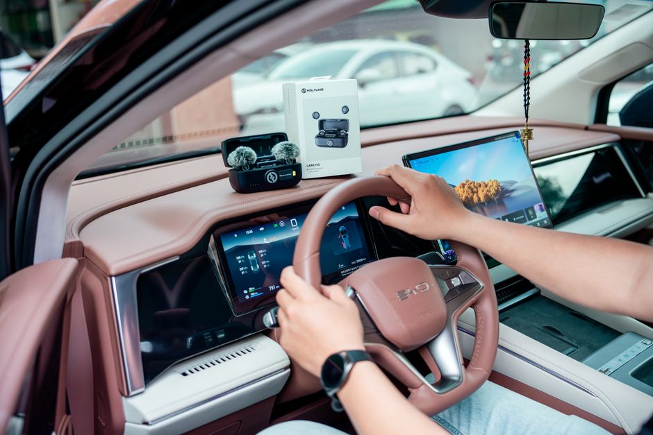 Interior view of a modern car with technology gadgets and a person interacting with the dashboard.