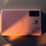 Stylish pink MA5R 5000 power bank with NFC feature in artistic lighting.