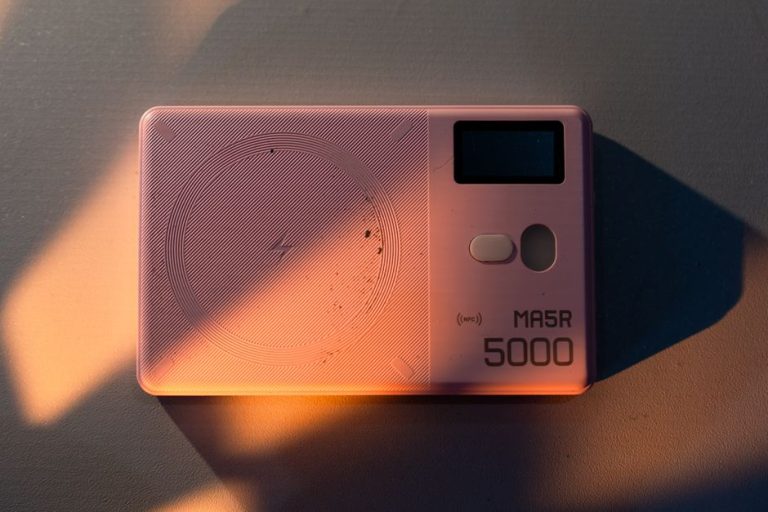 Stylish pink MA5R 5000 power bank with NFC feature in artistic lighting.