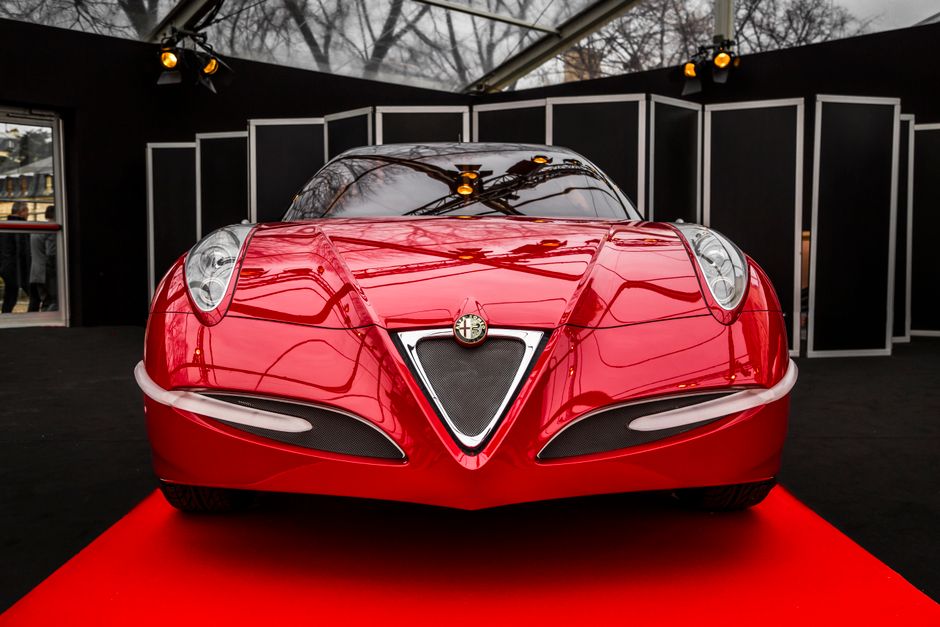 Front view of a sleek red Alfa Romeo concept car, showcased indoors with striking reflections.