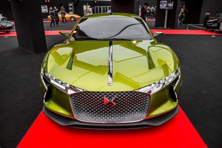 Front view of a shiny green sports car showcased at an auto exhibition.
