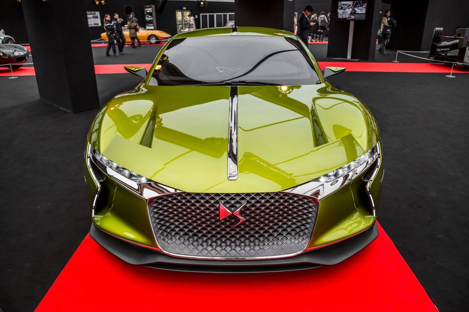 Front view of a shiny green sports car showcased at an auto exhibition.