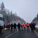 A group of people gather around a truck accident on a snowy Russian road.