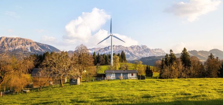 Wind turbine amidst lush country landscape with mountains. A serene depiction of renewable energy in nature.