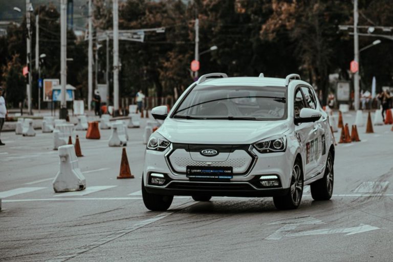 White car racing during urban rally and driving down paved street in daylight