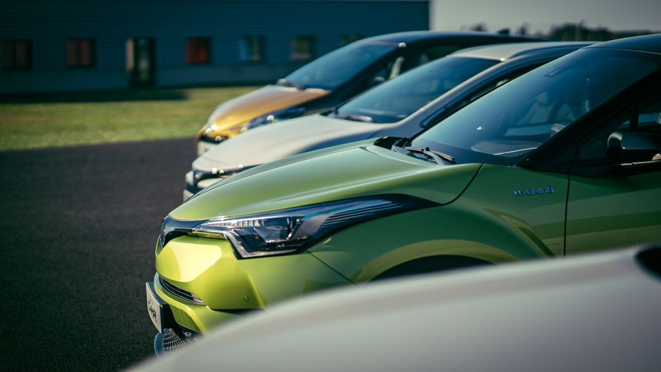 A row of brightly colored cars parked outdoors under daylight, showcasing their vibrant paint and shiny exteriors.