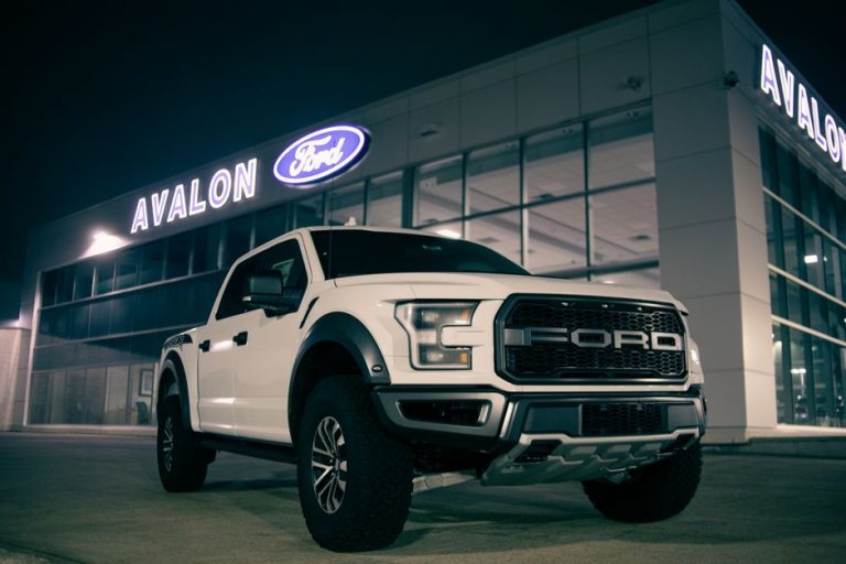 Low angle of modern pickup car with label on bumper on parking lot near retailing salon