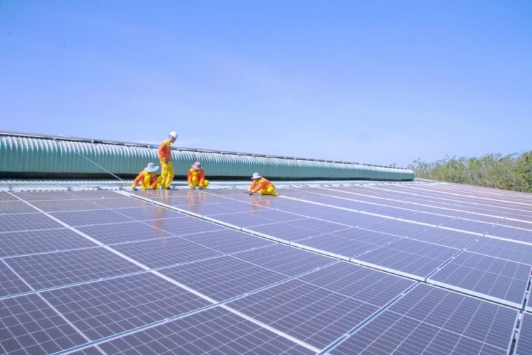 Team of workers installing solar panels on a large rooftop, promoting renewable energy and sustainability.