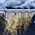 Dramatic aerial shot of a frozen dam with rushing water in winter in Minnesota.