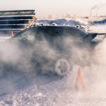 Car drifting on a snowy racetrack in Saint Petersburg, leaving a trail of smoke and snow.