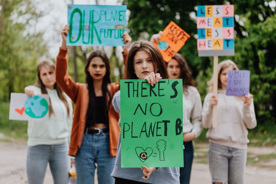 Group of young women protesting for climate change with signs outdoors. Environmental activism theme.